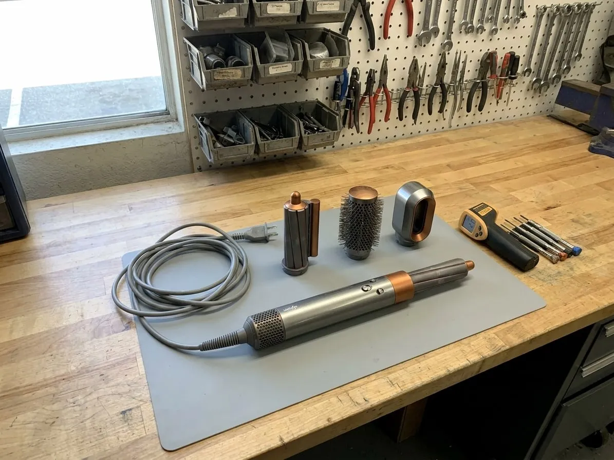 Dyson Airwrap multi-styler with its barrel, round brush and smoothing attachments on an anti-static mat