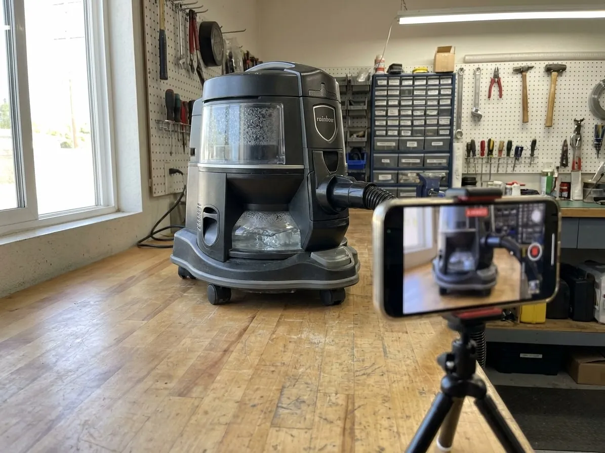 Phone on a tripod filming a Rainbow vacuum during its run test after repair