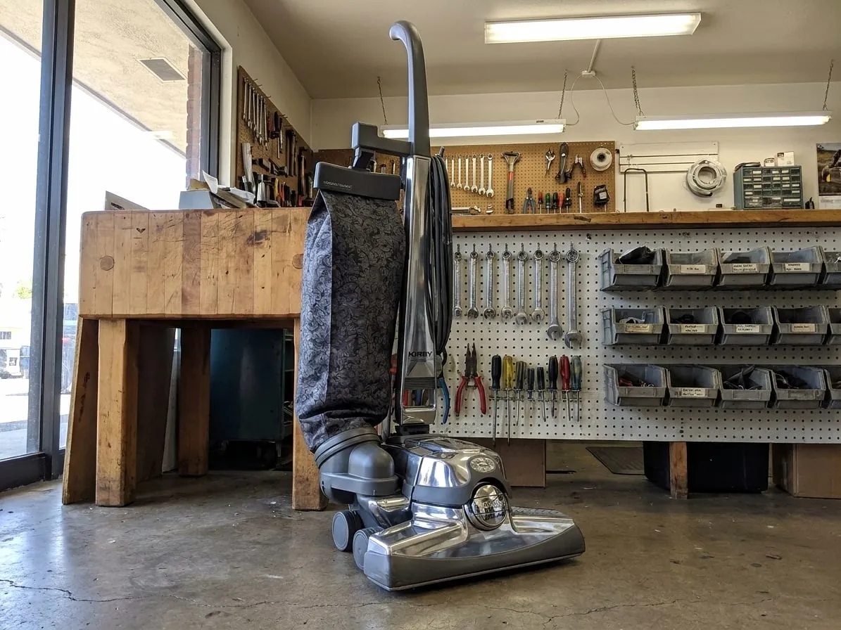 Kirby upright vacuum, cleaned and polished, standing in a repair workshop