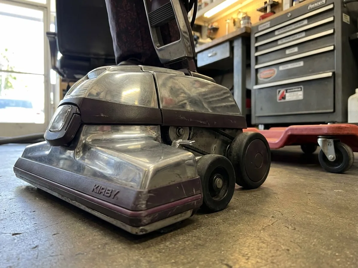 Kirby power nozzle with headlight and drive wheels on a workshop floor