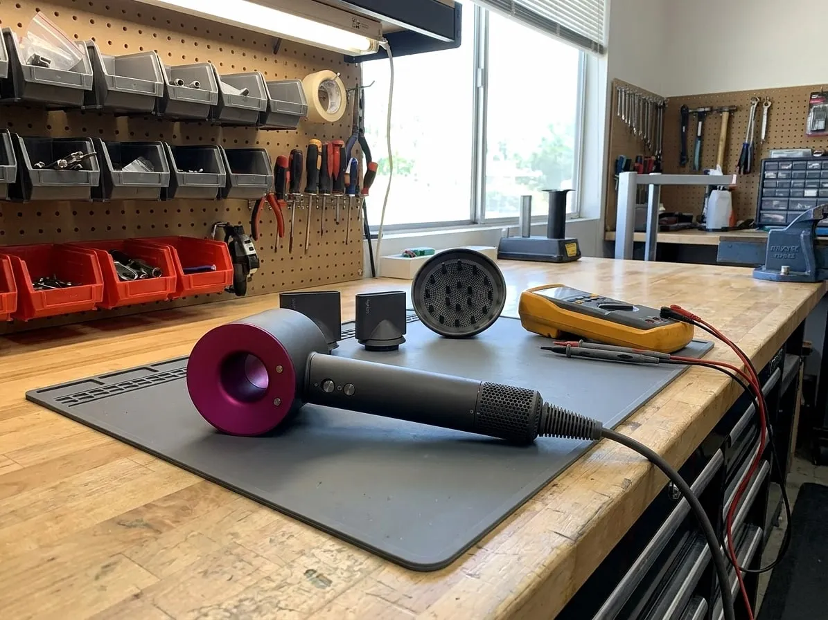 Dyson Supersonic hair dryer with its attachments and a multimeter on an anti-static mat